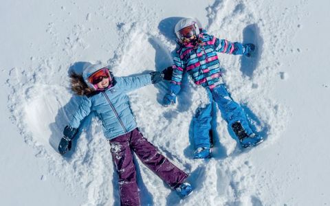 Zwei Kinder formen im Schnee Schmetterlinge